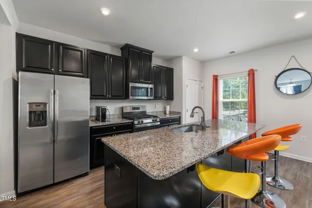 a kitchen with stainless steel appliances granite countertop a sink dishwasher a stove refrigerator and cabinets with wooden floor