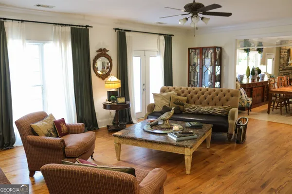 a living room with furniture couches and a dining table with wooden floor