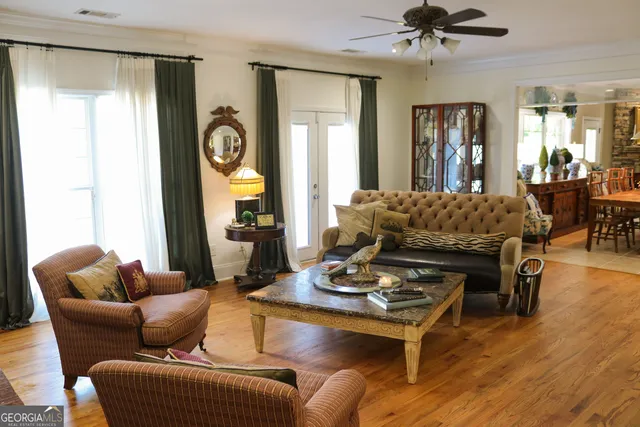 a living room with furniture couches and a dining table with wooden floor
