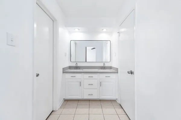 a view of a hallway with granite countertop white cabinets and a sink