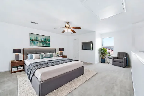 a spacious bedroom with a bed a couch and a flat screen tv
