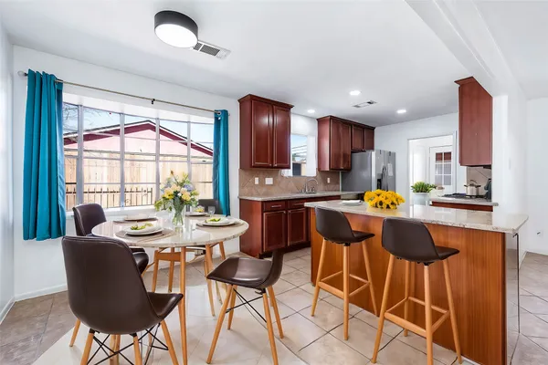 a kitchen with a dining table chairs and refrigerator