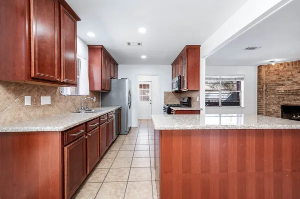 a kitchen with stainless steel appliances granite countertop a refrigerator a sink dishwasher and wooden cabinets with a granite countertops