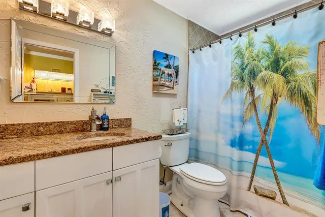 a bathroom with a granite countertop sink a toilet and a mirror