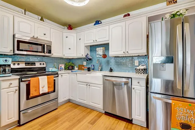 a kitchen with stainless steel appliances granite countertop a refrigerator sink and white cabinets
