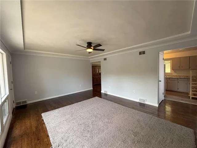 an empty room with wooden floor cabinet and windows