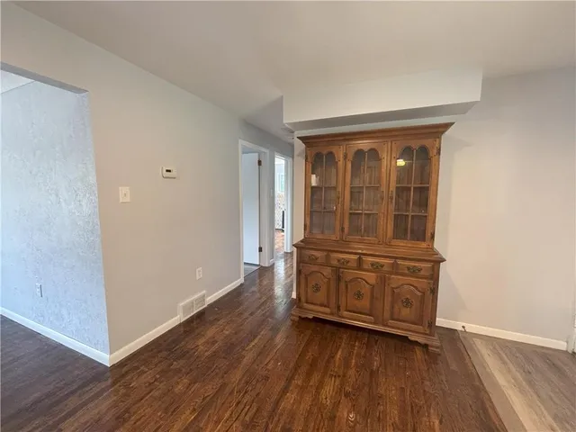 an empty room with wooden floor cabinet and windows