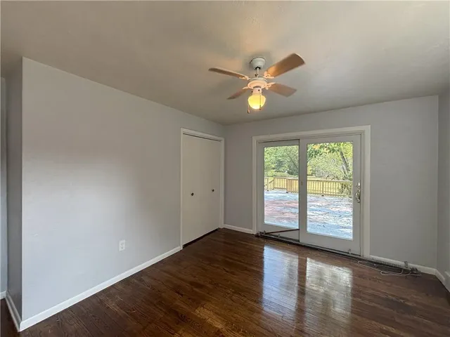 a view of an empty room with window and wooden floor