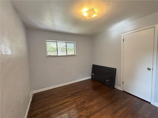 an empty room with wooden floor a cabinet and windows