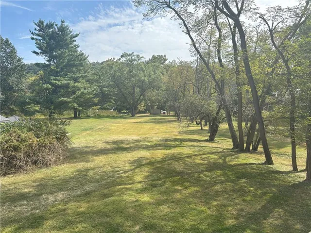 a view of a swimming pool with a yard and large trees