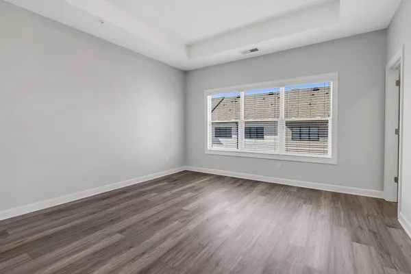 a view of an empty room with wooden floor and windows