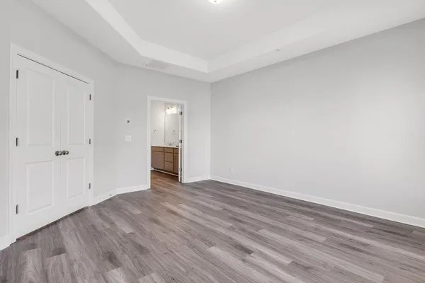 a view of an empty room with wooden floor and closet