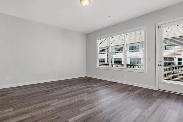 a view of an empty room with wooden floor and windows