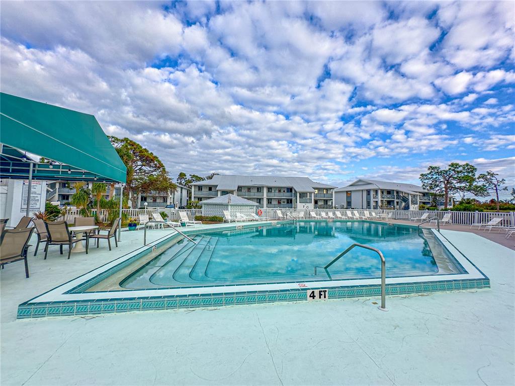 6800 Placida Road, Unit 268 Englewood, FL 34224 - Photo 23 of 33 a view of a swimming pool with a table and chairs under an umbrella