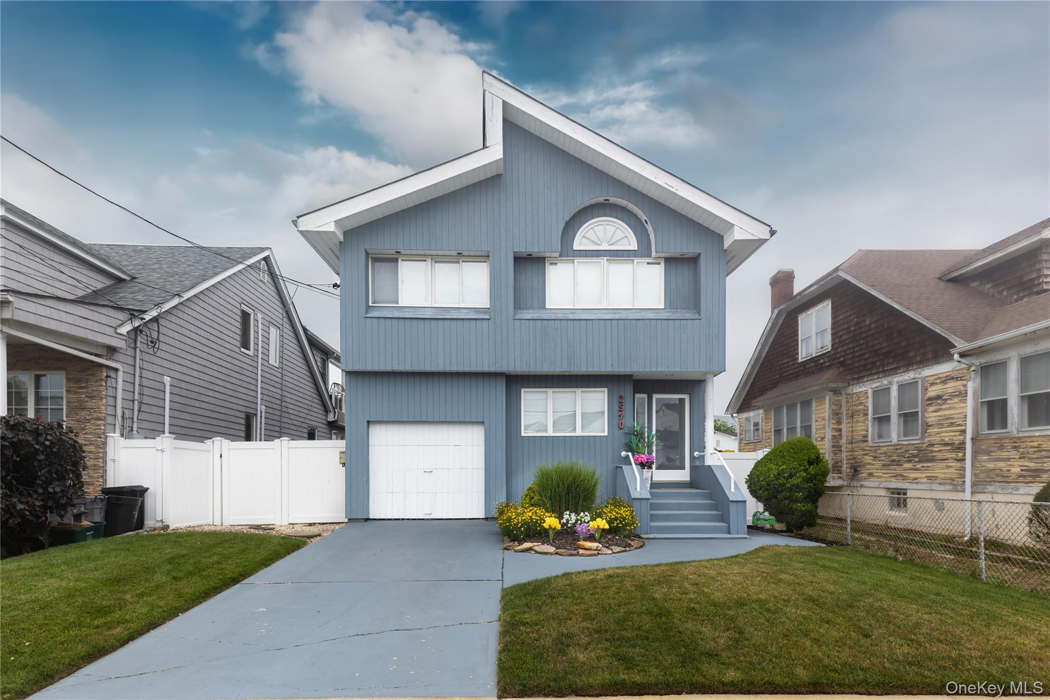 2590 Riverside Drive Wantagh, NY 11793 - Photo 1 of 27 Two-story residence featuring light blue siding, a white garage door, and a light gray concrete driveway
