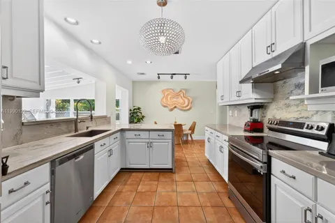 a large kitchen with stainless steel appliances granite countertop a lot of counter space and a sink