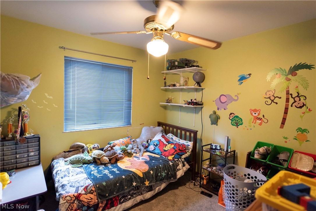 400 Baldwin Road Akron, OH 44312 - Photo 19 of 43 Bedroom 2 featuring a window with horizontal blinds, fun wall decor, overhead ceiling fan with light fixture, and wall-mounted shelving
