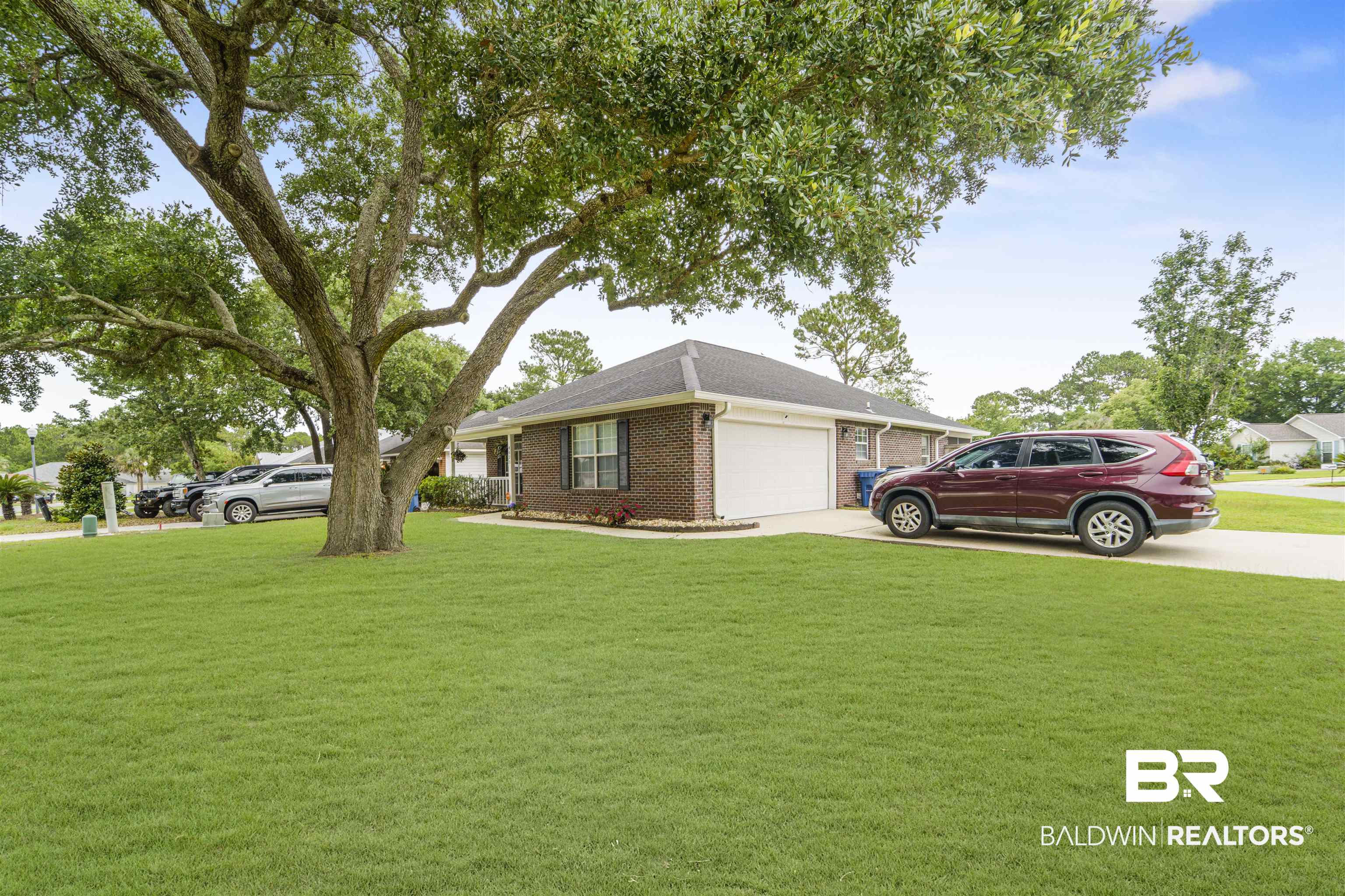 4620 Pine Boulevard Orange Beach, AL 36561 - Photo 4 of 49 View of front of home with an attached garage, driveway, brick siding, a front yard, and roof with shingles