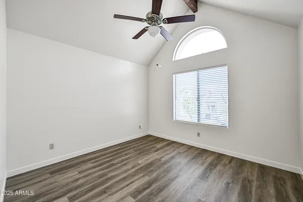 an empty room with wooden floor chandelier fan and windows