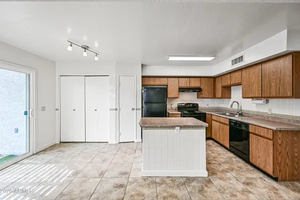 a kitchen with stainless steel appliances granite countertop a stove top oven a sink a refrigerator and white cabinets