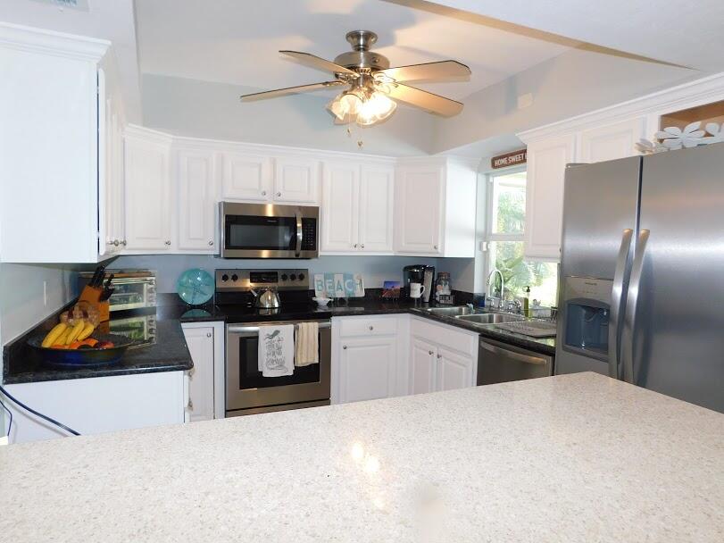 1150 Emerald Lane Singer Island, FL 33404 - Photo 8 of 25 a kitchen with stainless steel appliances granite countertop a refrigerator a stove a microwave oven a sink dishwasher with a dining table and chairs