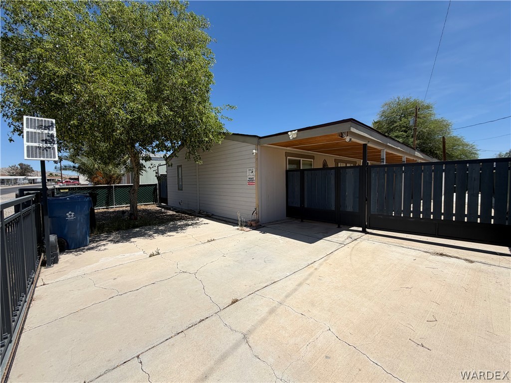 1910 Rio Grande Road Bullhead City, AZ 86442 - Photo 3 of 29 Paved driveway with a dark-toned privacy fence and sliding???????????????????????????????? gate