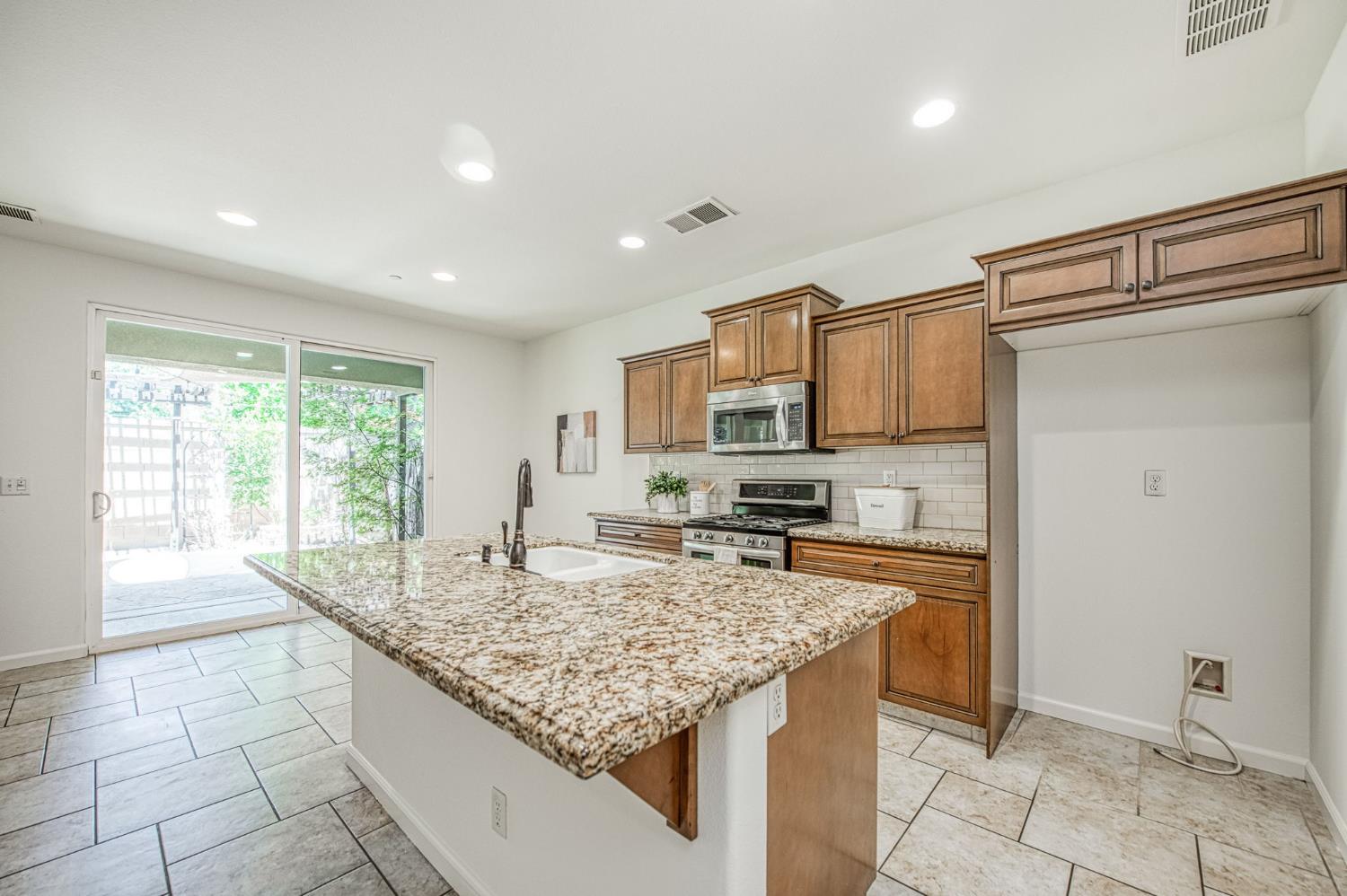 3521 Buckingham Avenue Clovis, CA 93619 - Photo 14 of 33 a kitchen with granite countertop kitchen island stainless steel appliances a sink stove and cabinets