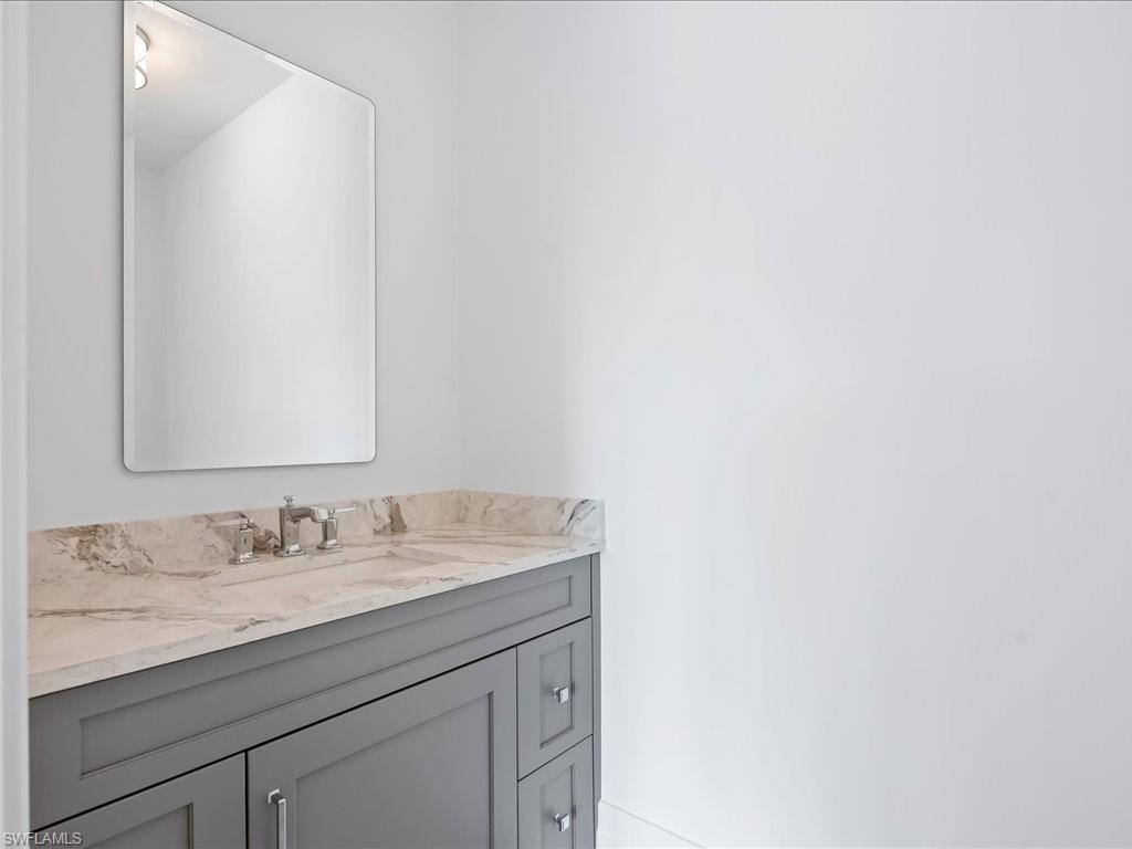 745 12th Avenue South, Unit 102 Naples, FL 34102 - Photo 31 of 50 a bathroom with a granite countertop sink and a mirror