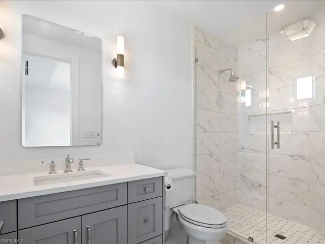a bathroom with a granite countertop sink a toilet and a mirror