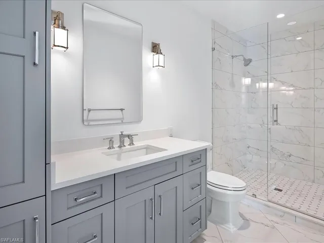a bathroom with a shower sink vanity mirror and toilet