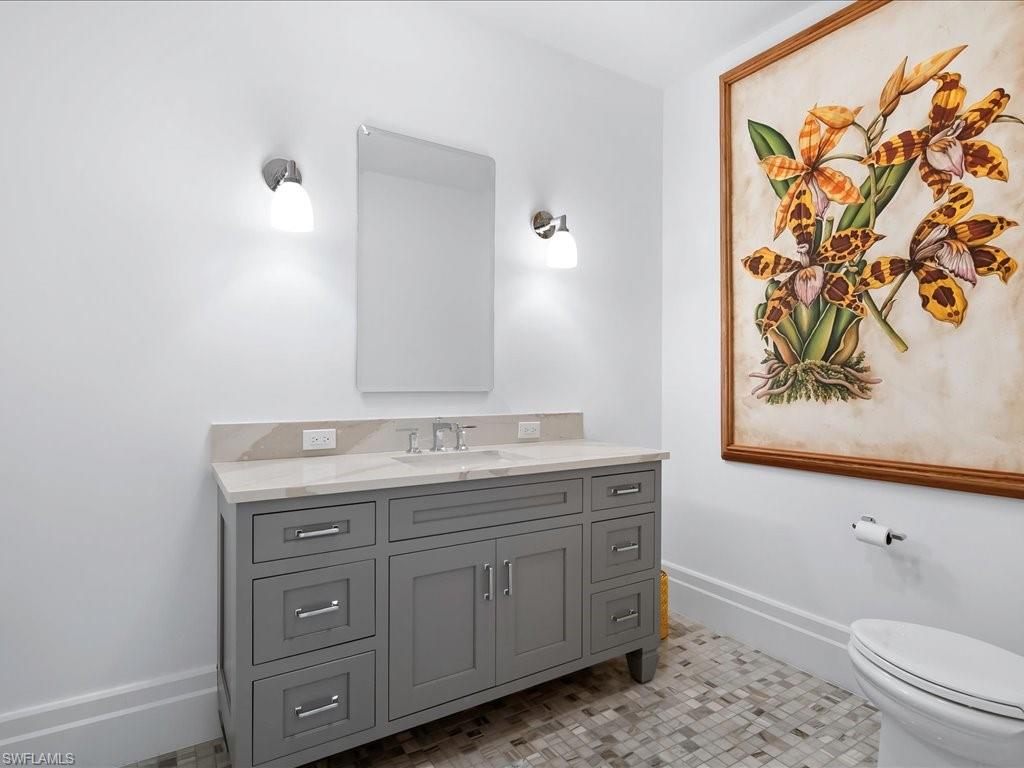 745 12th Avenue South, Unit 102 Naples, FL 34102 - Photo 40 of 50 a bathroom with a granite countertop sink a toilet and a bathtub