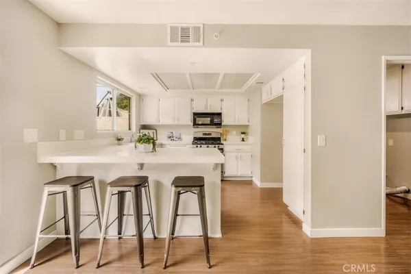 a kitchen with stainless steel appliances granite countertop a table chairs sink and cabinets