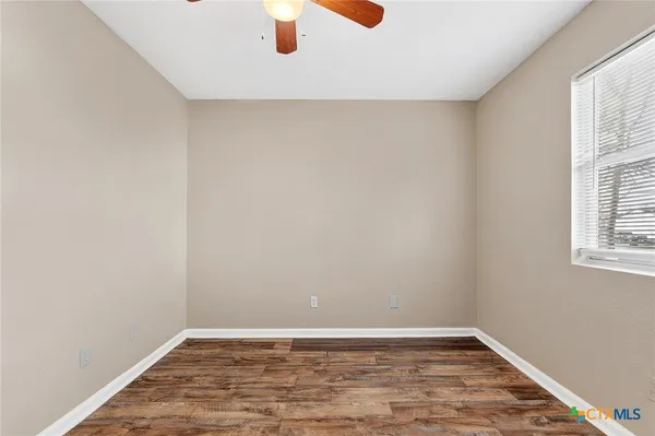 a view of an empty room with wooden floor and a window