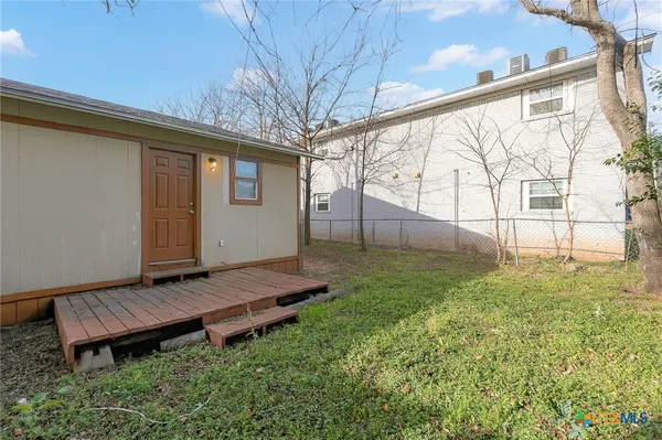 a view of a backyard with wooden fence and a bench