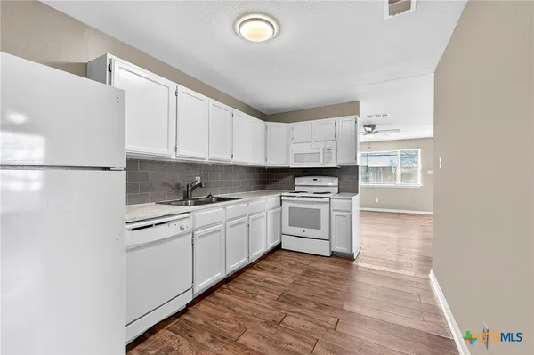 a kitchen with granite countertop white cabinets and white appliances