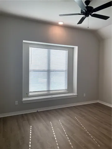 an empty room with wooden floor fan and windows
