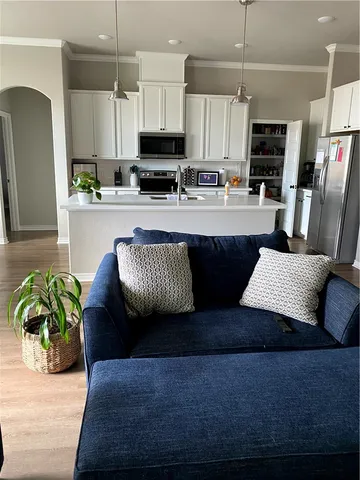 a living room with stainless steel appliances kitchen island granite countertop a couch wooden floor and a view of kitchen
