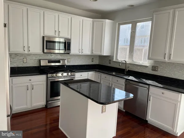 a kitchen with stainless steel appliances granite countertop white cabinets a sink and dishwasher with wooden floor