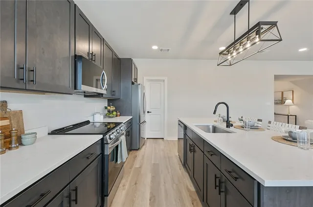 a kitchen with stainless steel appliances granite countertop a sink a stove cabinets and wooden floor