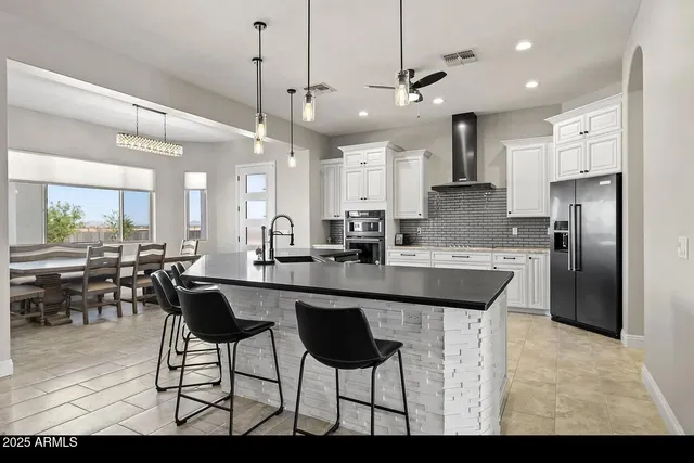 a kitchen with stainless steel appliances kitchen island granite countertop a stove a sink a center island a refrigerator and a wooden floor