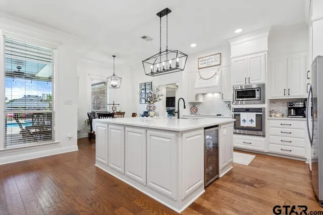a kitchen with white cabinets stainless steel appliances and dining table