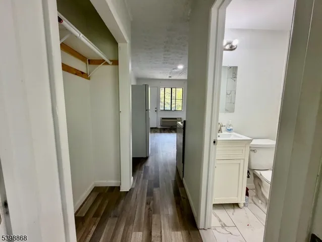 a view of a hallway with wooden floor and a bathroom