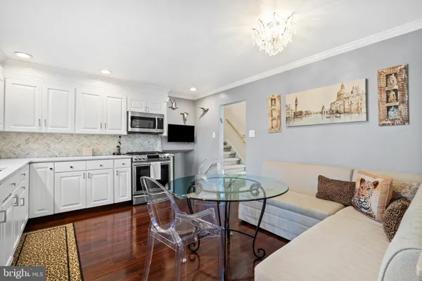 a kitchen with stainless steel appliances granite countertop a stove top oven a white dining table and chairs with wooden floor
