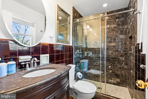 a bathroom with a granite countertop sink toilet a mirror and shower