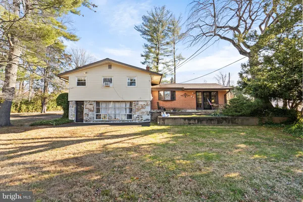 a view of a house with a yard and a large tree
