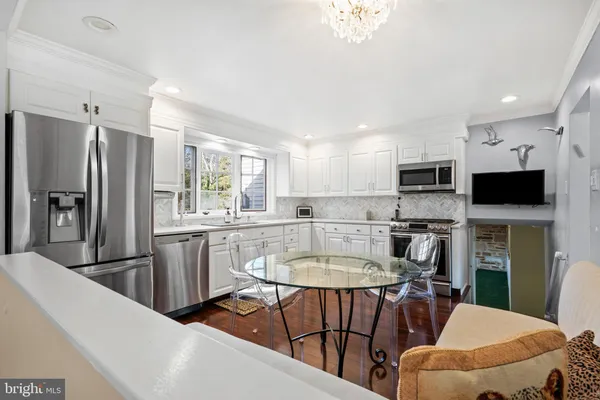 a kitchen with stainless steel appliances a dining table chairs microwave and sink