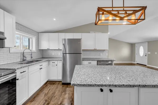 a kitchen with stainless steel appliances granite countertop a sink refrigerator and cabinets