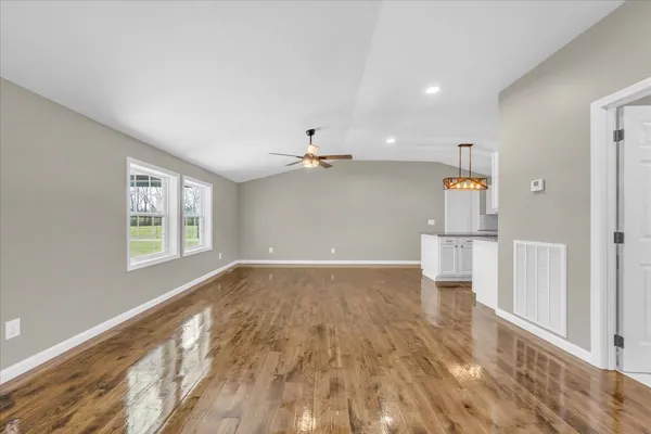 a view of empty room with wooden floor and fan