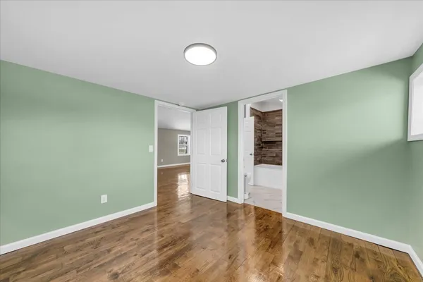 a view of an empty room with wooden floor and closet