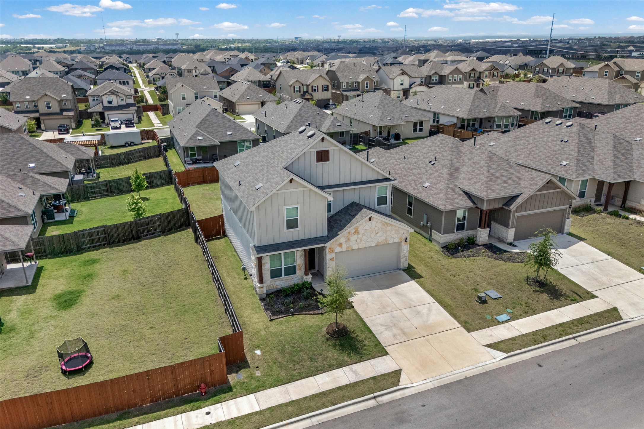 208 Orange Road Buda, TX 78610 - Photo 29 of 31 An aerial perspective reveals a contemporary two-story home with a stone and siding facade amidst a well-maintained neighborhood.